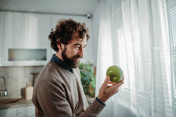 istock Man holding green apple thinking about healthy eating 2249157077