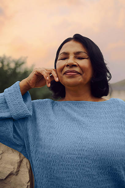 istock Middle Aged Woman Recharging Outdoors Wearing Light Blue Sweater Relaxing 2249159078