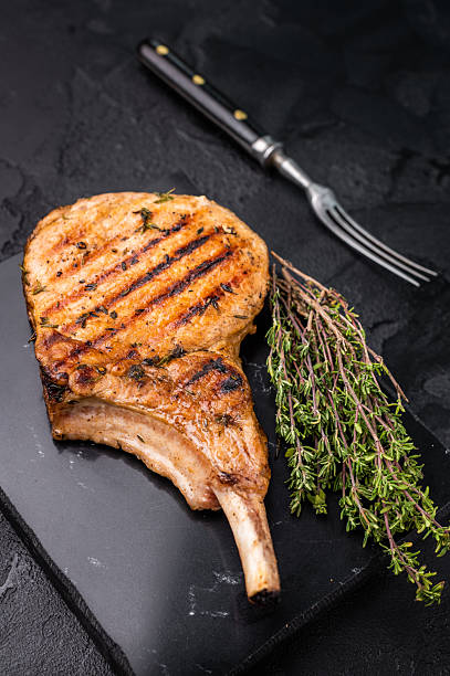 istock Savory bone in pork chop steak, beautifully charred and ready to impress at your next barbecue gathering.  black background. top view 2249167155