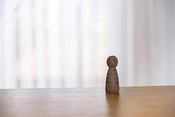 A small wooden cat figurine standing on a smooth wooden surface with a soft, bright, out-of-focus background. The minimalist composition and neutral tones create a calm, modern, and cozy atmosphere suitable for concepts such as simplicity, childhood, decor, mindfulness, and interior design.