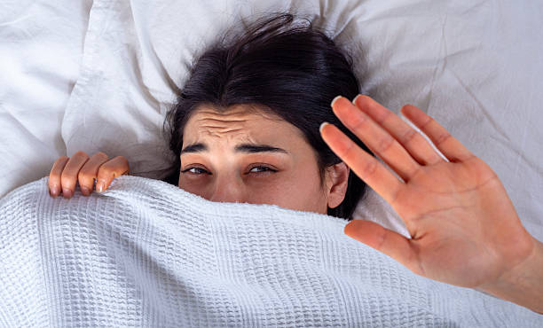 istock young woman hiding in bed from violence 2249168432