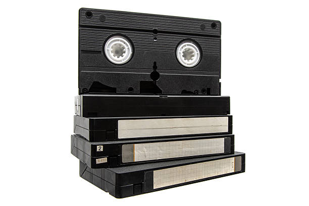 Stack of black VHS video cassettes with one upright, isolated on a white background.