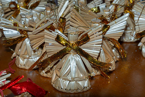 Close-up of numerous small angel-shaped souvenirs woven from straw.