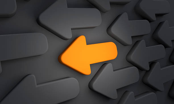 istock Orange arrow points in the left direction surrounded be black arrows. 2249174869