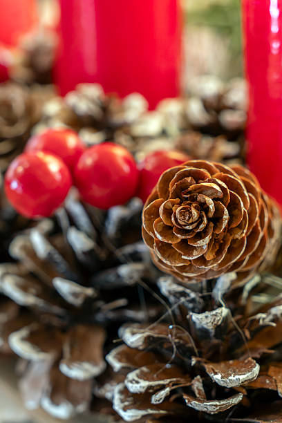 A beautifully arranged display featuring a pine cone, red berries, and vibrant candles, creating a warm and inviting atmosphere for winter festivities.