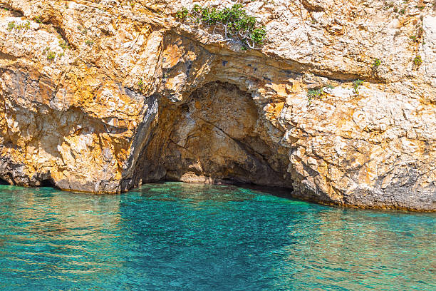 Scenic coastal cave with turquoise water and rocky cliffs.