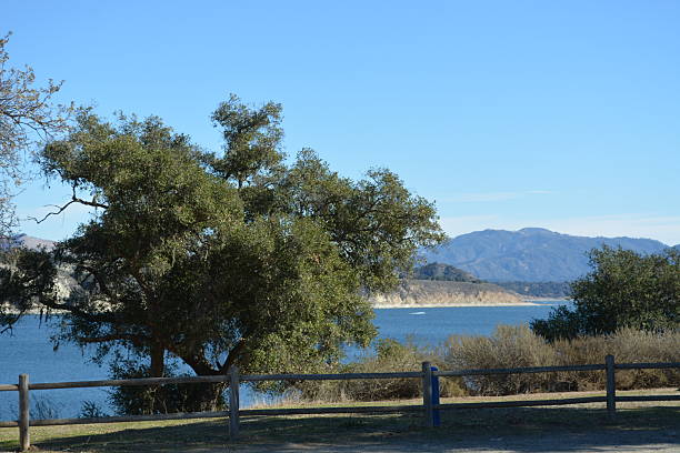 istock Serene Lakeside View With Lush Trees and Distant Mountains Under a Clear Blue Sky 2249179882