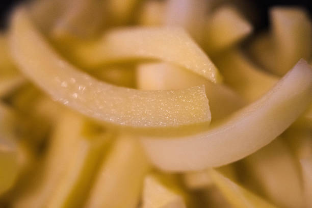 A bowl of raw yellow potatoes cut into sticks for fries held in hands