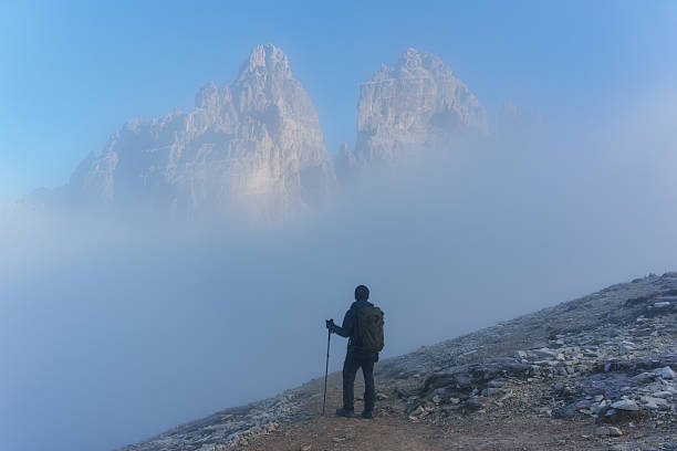 Mid adult man with hiking pole standing and looking at view at sunset in mountain