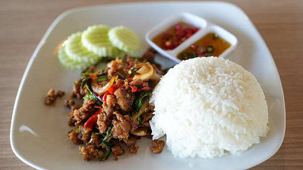 Delicious Spicy Pad Krapow Moo on a White Plate with Crisp Cucumber
