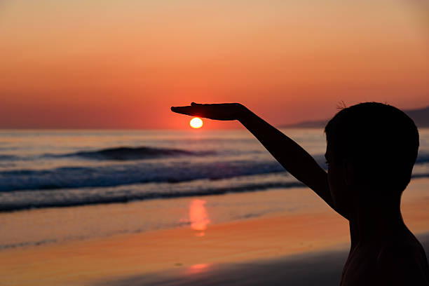 istock The boy is playing with the sun. Boy on the beach with sunset. 2249187233