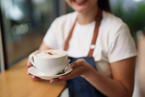 Barista presenting hot cappuccino with smile in cafe