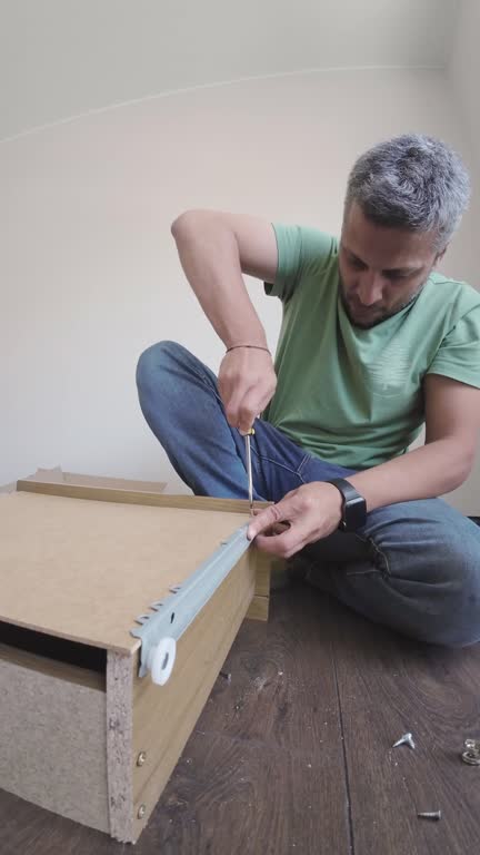 Man Assembling Wooden Furniture with Screwdriver