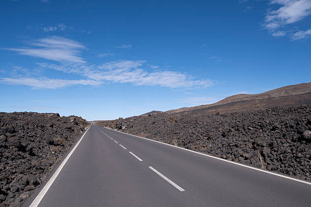 Rock formations and the rugged mountain slopes of El Teide National Park in Tenerife. The scene highlights layered lava structures, earthy tones, and the distinct summit of Teide under a deep blue sky — ideal for concepts of geology, wilderness, natural landscapes, volcanic environments, and conservation areas.