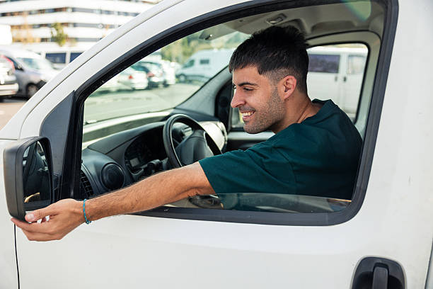 istock Happy delivery driver adjusting side mirror of van 2249202371