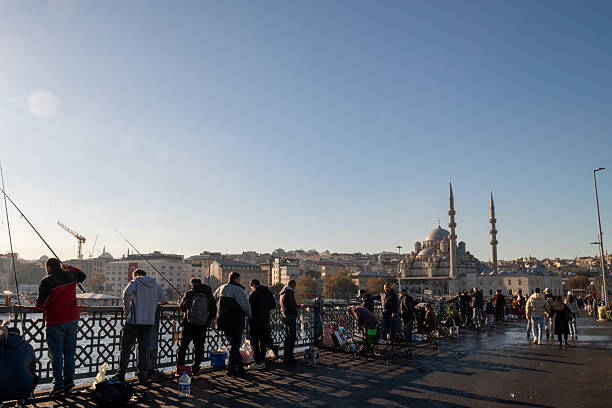 Locals fishing off of Galata Bridge in Istanbul with the Eminönü neighborhood and Yeni Mosque in sight on the Turkey Republic Day.