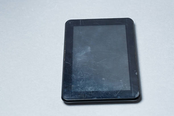 istock Black scratched tablet with a protective film on a gray background. Protect your device screen 2249211152
