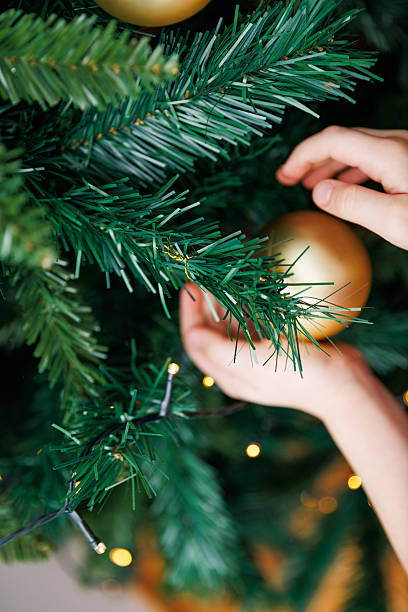 istock Child Hanging Golden Ornament on Christmas Tree 2249216813