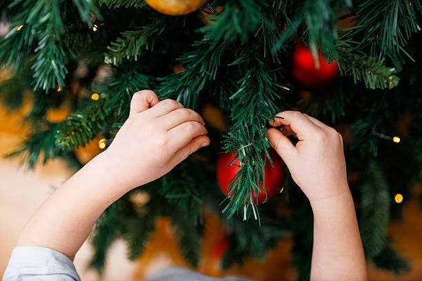 istock Child Decorating Christmas Tree with Red Ornaments 2249216836