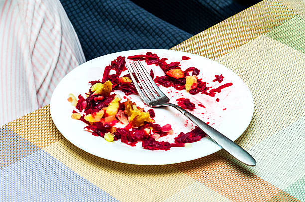 Plate of leftover salad with fork on a colorful patterned tablecloth