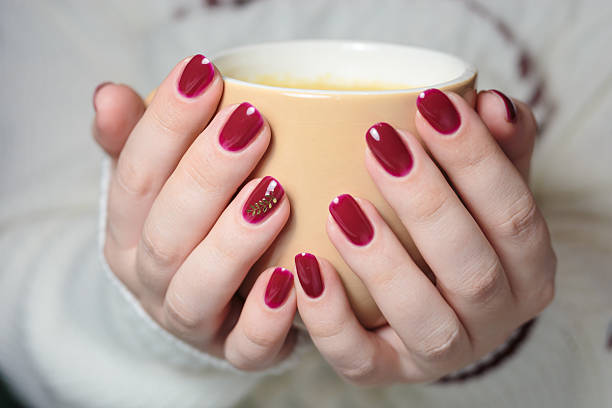istock Two hands with elegant red nail polish cradle a warm cup of tea. The nails feature a delicate leaf design, creating a cozy atmosphere perfect for relaxation. 2249218937