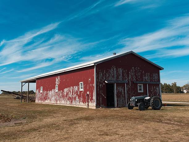 istock Weathered red barn with vintage farm tractor under an azure blue sky 2249219021