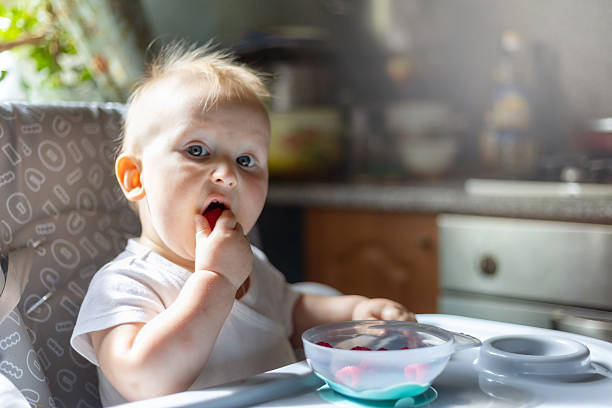 istock Baby Eating Raspberries in High Chair 2249220247