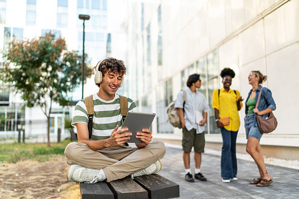 istock Young male student using tablet and headphones on campus 2249222787