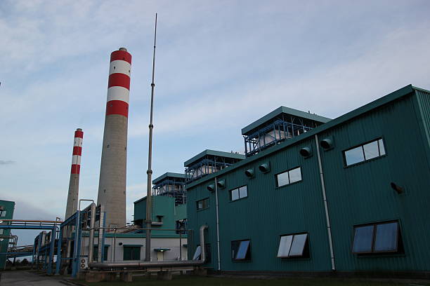 istock Industrial complex features tall chimney stacks and metal buildings under a cloudy sky. 2249225323