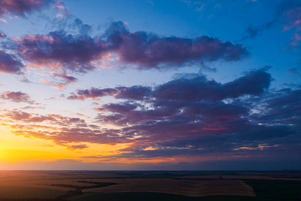 Stunning sunset sky with clouds over green hills. Summer countryside view.