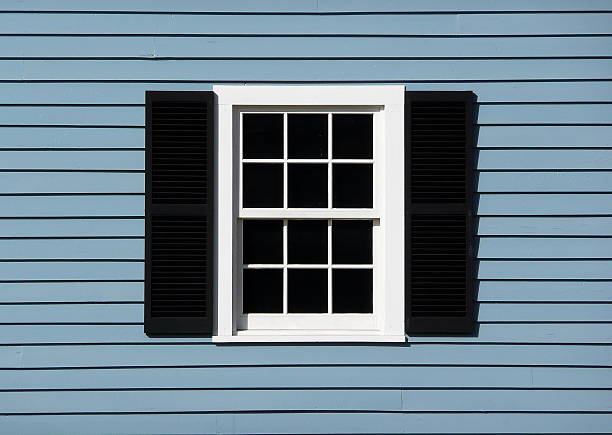 istock Symmetrical White Window with Black Shutters on Blue Siding 2249232818