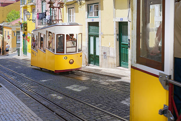 Lisbon, Portugal May 29, 2024: The iconic yellow Elevador da Bica funicular climbs the steep, cobbled Rua da Bica de Duarte Belo in Lisbon, capturing the city's unique charm and architecture