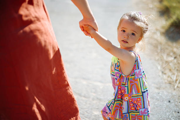 Loving mom playing outside with her daughter. Happy young father and daughter having fun while running in spring day at the park. Blooming trees