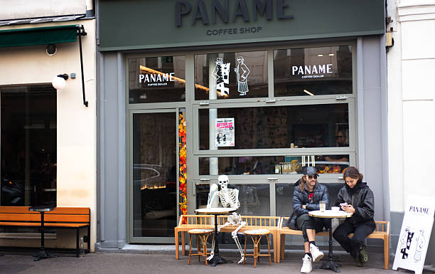A small yellow coffee cup on a purple table in Mortmartre, Paris, with tourists and shops as background