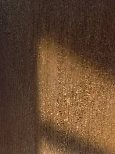 istock Soft sunlight casting diagonal shadows on a wooden cabinet surface creating a warm natural texture. 2249245695