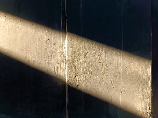 istock Soft sunlight forming a long glowing beam on a textured wall creating warm contrast. 2249245880