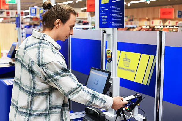 istock A man uses a smartphone to pay at a modern self-service terminal at a grocery store or supermarket. 2249247471