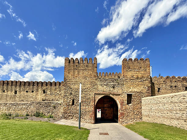 Telavi, Georgia - April 26 2025: Visitors approach the majestic entrance of King Erekle II Palace in Telavi Georgia under a vibrant blue sky with clouds.
