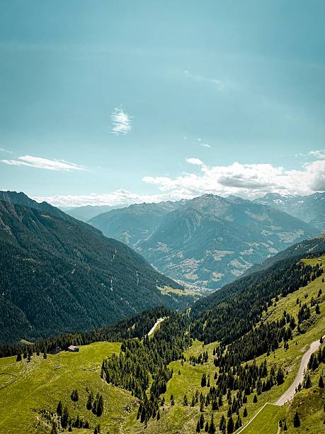 Panoramic view into Passeier Valley (germ. Passeiertal) from Jaufenpass in South Tyrol, Italy with winding mountain road, green pastures and forested slopes under a blue sky