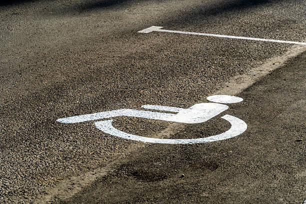 istock A clear white disabled parking symbol is painted on the asphalt surface, indicating an accessible space for wheelchair users. 2249254272