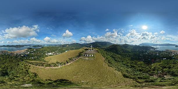 Wide aerial panorama of Mount Tapyas Viewdeck featuring cross and Coron sign overlooking town and Mount Delara under sunny sky