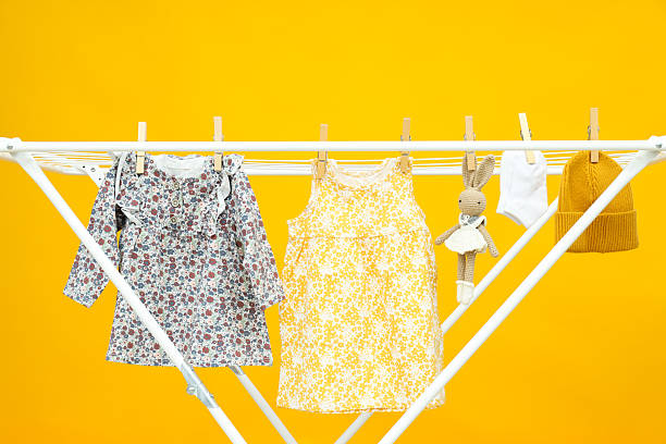 istock Child clothes and toy hanging and drying on drying rack on yellow background 2249256838