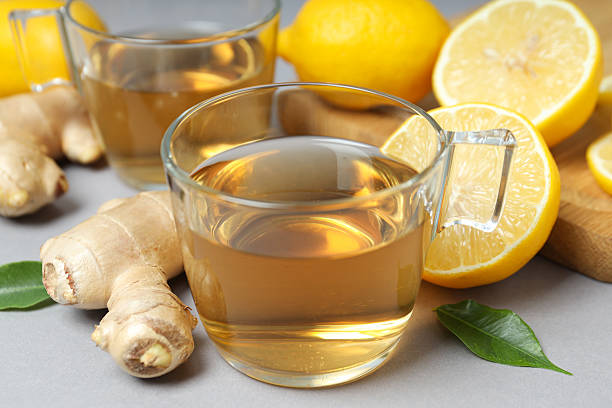 istock Cups of tea, ginger and lemons on gray background, close up 2249258208