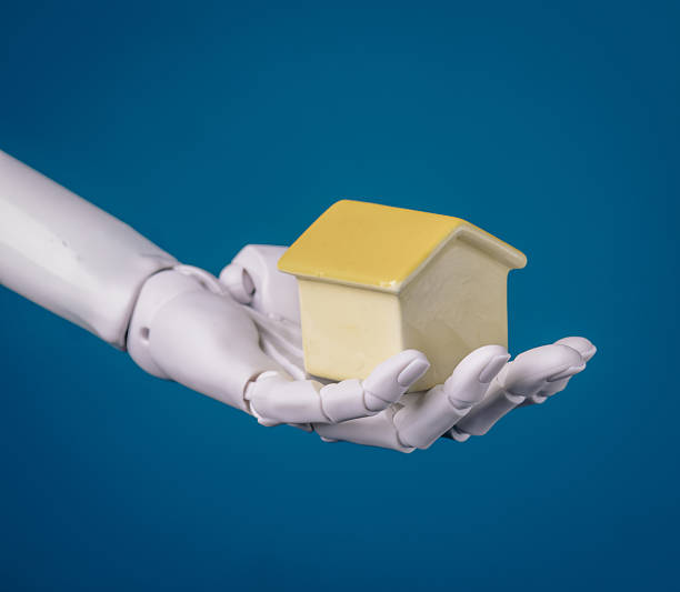 istock Smart Home Future: Robot Hand Holding a Miniature House on Blue Background 2249264045