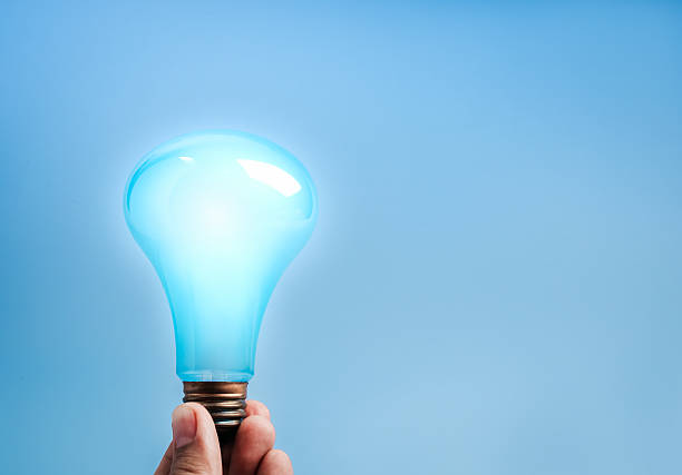 istock Hand holding glowing blue light bulb on blue background with copy space, symbolizing innovation, smart technology, creativity, AI solutions, and bright new ideas in modern business concepts. 2249264893