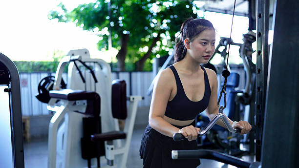 istock woman pulling down weights on a cable machine at the gym, training her biceps and building muscle strength. fitness center health workout concept 2249265392