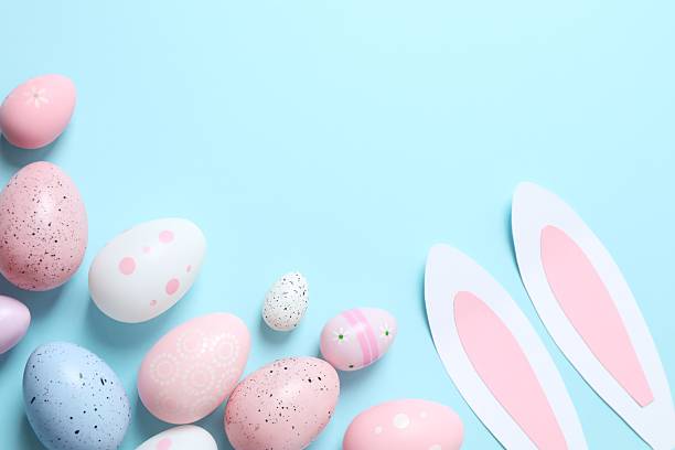 istock Happy Easter. Colorful eggs and Easter bunny ears on a pastel blue background, space for text or advertising 2249269489