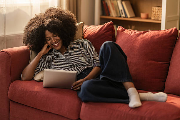 istock Happy black woman using digital tablet on sofa at home. 2249272904