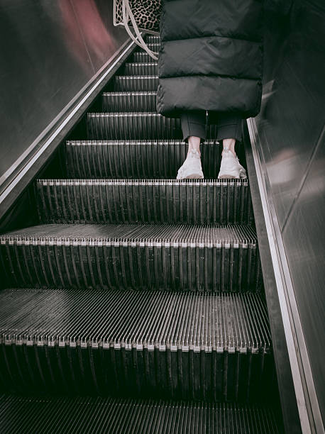 istock Person riding up escalator steps at public metro transit station 2249272957
