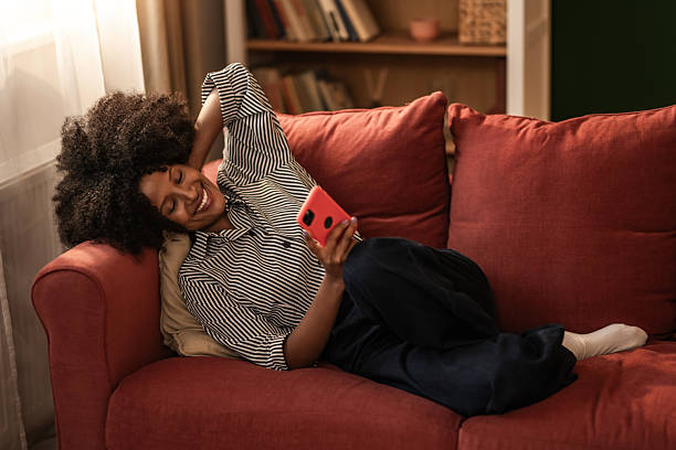 istock Happy black woman using phone on sofa at home. 2249273721